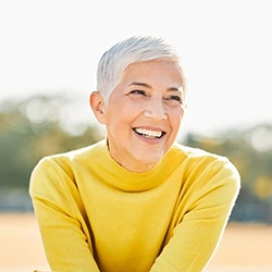 Older woman in yellow shirt smiling outside