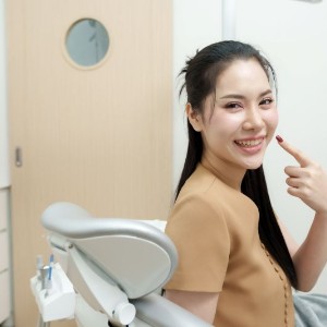 Happy dental patient pointing at her smile