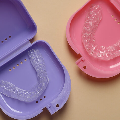 Two Invisalign clear aligners in storage cases
