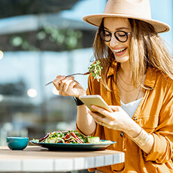 Happy young woman eating salad at outdoor café