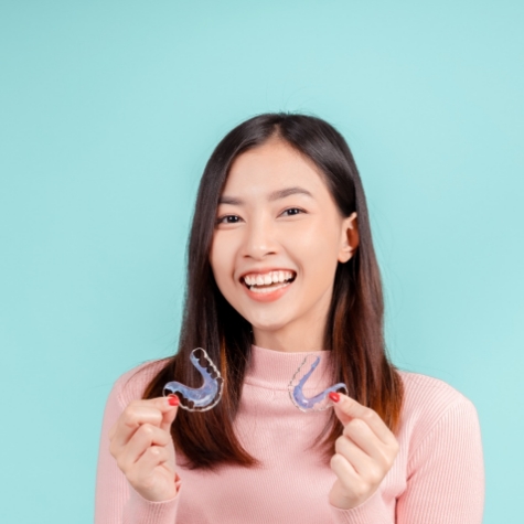 Happy teen girl holding two orthodontic retainers