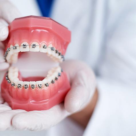 Gloved hands holding model with braces