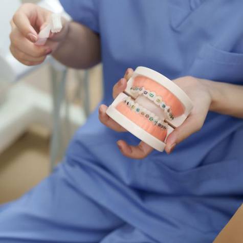 Dental team member demonstrating how to care for braces