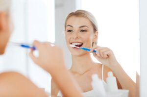 Young woman brushing her teeth in front of bathroom mirror