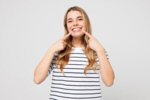 Happy woman pointing at her beautiful, straight teeth