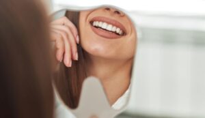 Patient's beautiful smile reflected in hand mirror