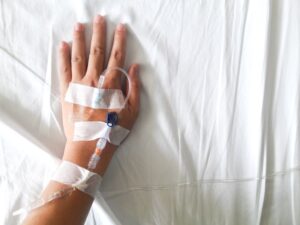 Hand with IV resting on white sheet