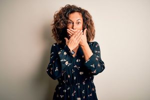 Embarrassed middle-aged woman covering her mouth 